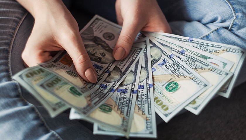 Woman with $100 bills spread open in hands