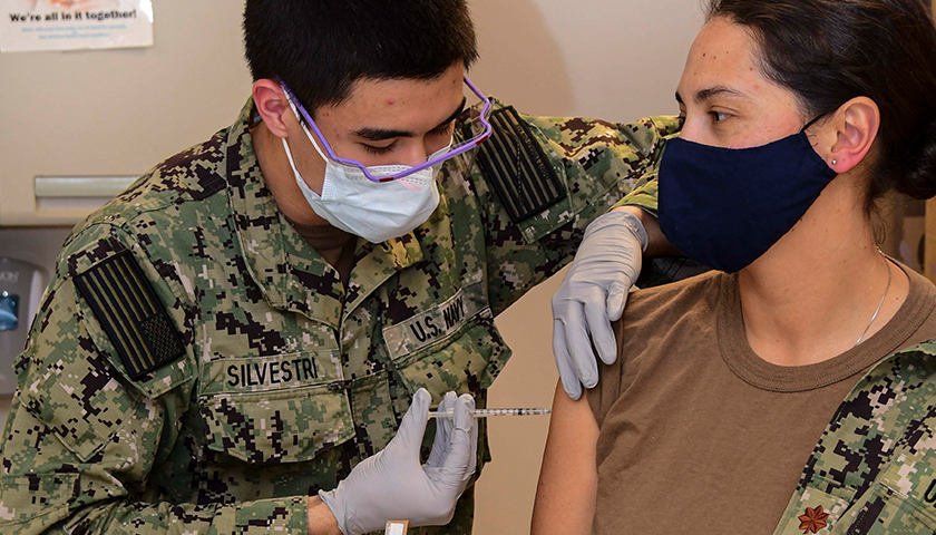 PORTSMOUTH, Va. (Dec. 15, 2020) – Hospitalman Roman Silvestri administers one of the first COVID-19 vaccines given at Naval Medical Center Portsmouth (NMCP) to Lt. Cmdr. Daphne Morrisonponce, an emergency medicine physician, Dec. 15. NMCP was one of the first military treatment facilities (MTF) selected to receive the vaccine in a phased, standardized and coordinated strategy for prioritizing and administering the vaccine. (U.S. Navy photo by Seaman Imani N. Daniels/Released)