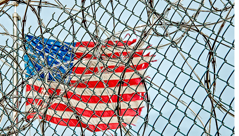 American flag behind barbed wire and fence